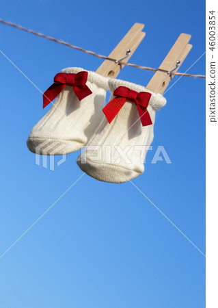 Newborn sock with red ribbon hung on wooden clothespin against blue sky. Baby, parenting, childbirth, happiness, love image 46003854