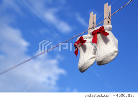 Newborn sock with red ribbon hung on wooden clothespin against blue sky. Baby, parenting, childbirth, happiness, love image 46003855