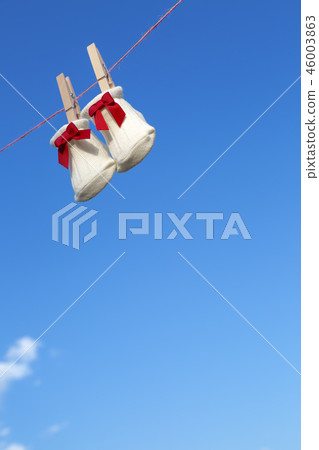 Newborn sock with red ribbon hung on wooden clothespin against blue sky. Baby, parenting, childbirth, happiness, love image 46003863