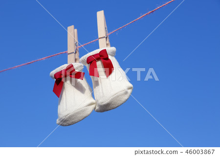 Newborn sock with red ribbon hung on wooden clothespin against blue sky. Baby, parenting, childbirth, happiness, love image 46003867
