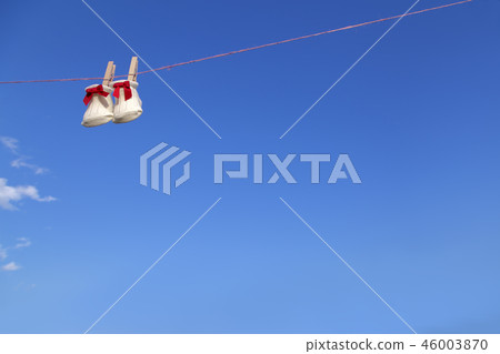 Newborn sock with red ribbon hung on wooden clothespin against blue sky. Baby, parenting, childbirth, happiness, love image 46003870