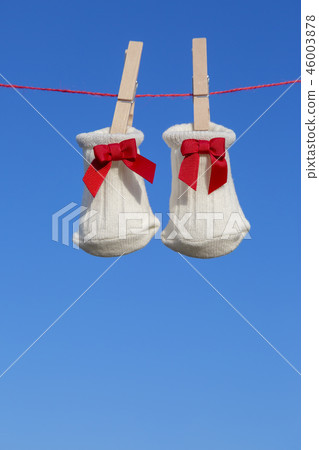 Newborn sock with red ribbon hung on wooden clothespin against blue sky. Baby, parenting, childbirth, happiness, love image 46003878