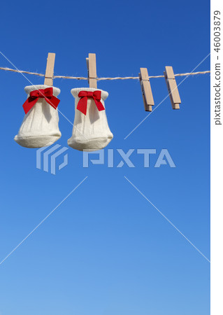 Newborn sock with red ribbon hung on wooden clothespin against blue sky. Baby, parenting, childbirth, happiness, love image 46003879