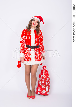 Holidays, Christmas and gifts concept - Beautiful woman in Santa costume with big and heavy bag of Holidays, Christmas and gifts concept - Beautiful woman in Santa costume with big and heavy bag of 46004064