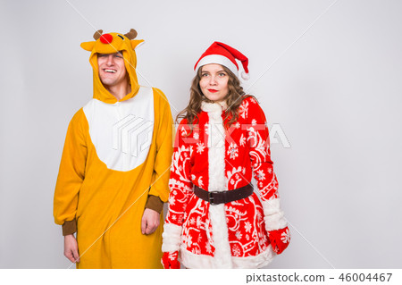 Fun, Christmas and holidays concept - happy woman in santa clothes with man in costume of deer are Fun, Christmas and holidays concept - happy woman in santa clothes with man in costume of deer are 46004467