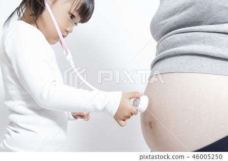 女孩的手用玩具聽診器檢查懷孕母親的大肚子。懷孕，上個月，父母和孩子，玩，生 46005250