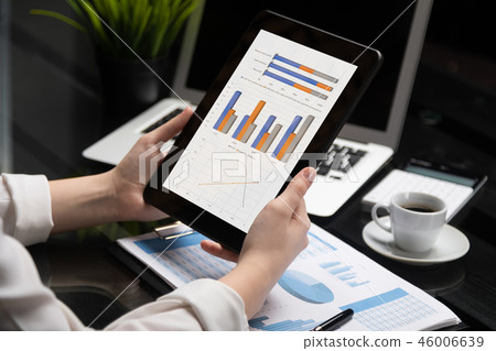 Close-up hands holding tablet on background of financial documents 46006639