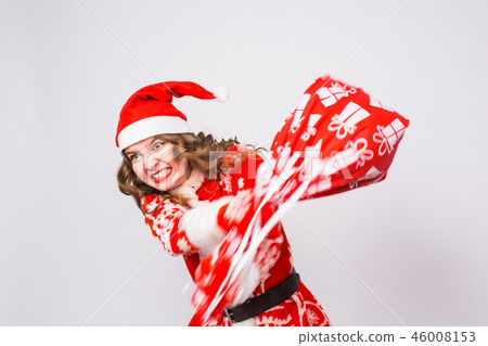 Holiday, Christmas and people concept - Angry woman in santa costume with bag of presents Holiday, Christmas and people concept - Angry woman in santa costume with bag of presents 46008153