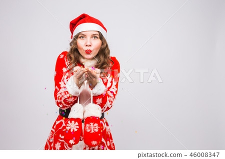 Beautiful girl in Santa's costume welcoming the new year 2019 blowing confetti to camera. New Year Beautiful girl in Santa's costume welcoming the new year 2019 blowing confetti to camera. New Year 46008347