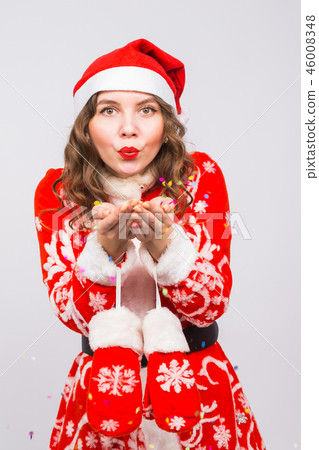 Christmas, people concept - woman in santa suit blowing colourful sequins on background with copy Christmas, people concept - woman in santa suit blowing colourful sequins on background with copy 46008348