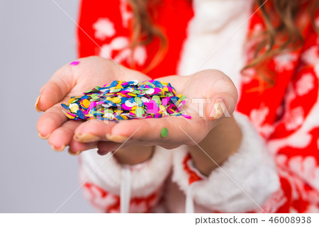 Celebrating, christmas concept - colourful confetti decorations and glitter in woman's hands close Celebrating, christmas concept - colourful confetti decorations and glitter in woman's hands close 46008938