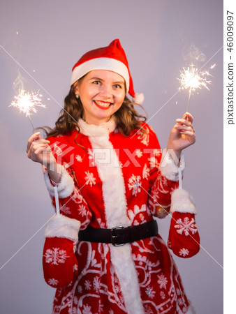 Christmas, holidays and people concept - woman in santa suit with lights and sparkles laughing. 46009097