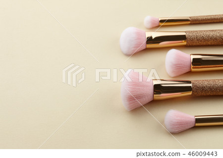Make up brushes close up on beige background Make up brushes close up on beige background 46009443