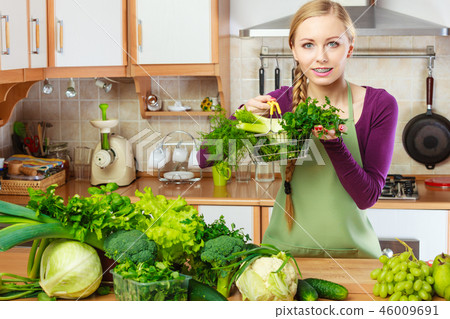 Woman in kitchen having vegetables holding shopping basket Woman in kitchen having vegetables holding shopping basket 46009691