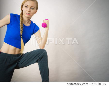Teenage woman working out at home with dumbbell Teenage woman working out at home with dumbbell 46010107