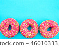 Three donuts with bright pink icing on blue  46010333