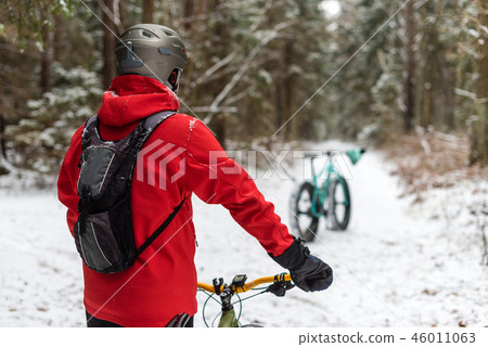 Guy in the red jacket keeps fatbike in the wood Guy in the red jacket keeps fatbike in the wood 46011063