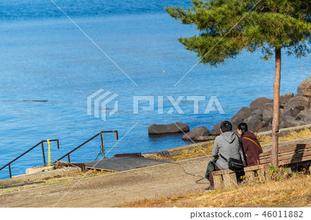 Men and women sitting on a lake and a bench Men and women sitting on a lake and a bench 46011882