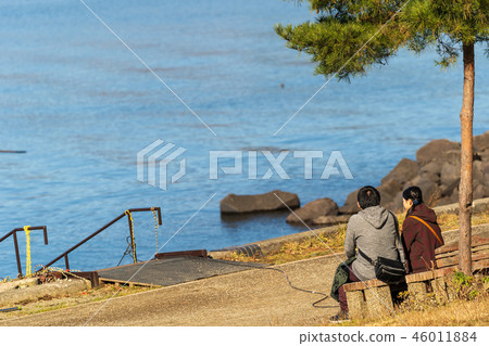 Men and women sitting on a lake and a bench Men and women sitting on a lake and a bench 46011884