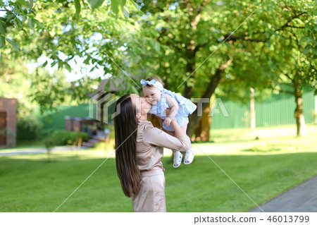 Young mother holding little female baby in garden. Young mother holding little female baby in garden. 46013799