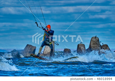 A male kiter slides on the surface of the water A male kiter slides on the surface of the water 46018994