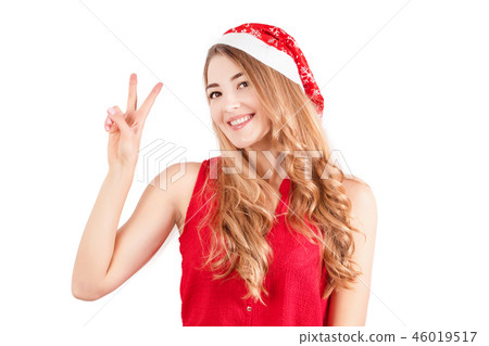 Woman in santa hat isolated on white. Happy girl posing showing peace gesture Woman in santa hat isolated on white. Happy girl posing showing peace gesture 46019517