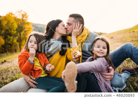 A portrait of young family with two small children in autumn nature at sunset, kissing. 46020893