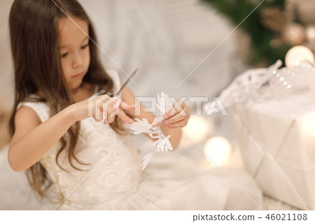 child girl makes paper snowflakes for decoration Christmas tree child girl makes paper snowflakes for decoration Christmas tree 46021108