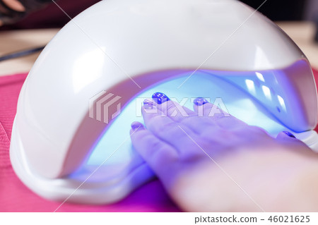 Manicured nails in UV lamp. Rays cure gel polish Manicured nails in UV lamp. Rays cure gel polish 46021625