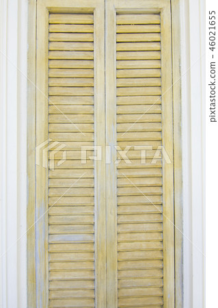 Yellow window shutters and white wall of a house  46021655