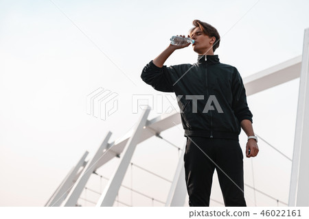 Young stortsman is drinking water near the stadium Young stortsman is drinking water near the stadium 46022161