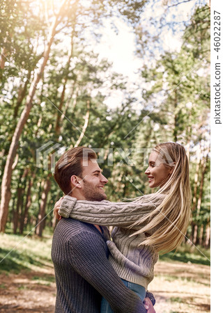 Young man holding his girlfriend on hands in autumn forest. 46022287