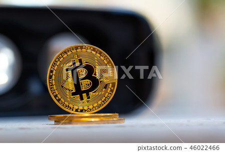 A gold bitcoin cryptocurrency coin on a desktop A gold bitcoin cryptocurrency coin on a desktop 46022466