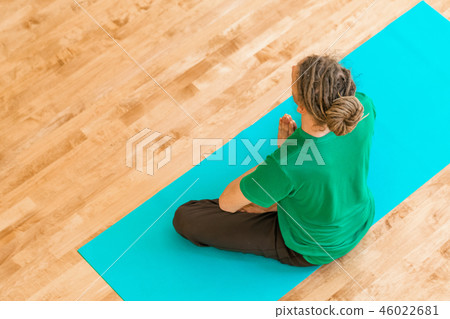 Man in a meditation pose inside a bright room 46022681