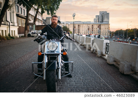Biker poses on chopper in city, front view 46023089
