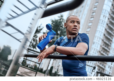 Young african man at the open air gym is resting with water 46023116