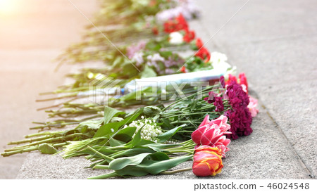 Flowers on granite slab of monument to soldiers. 46024548