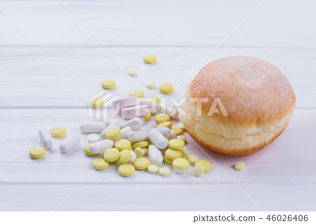 Donut and pills on wooden background. Donut and pills on wooden background. 46026406