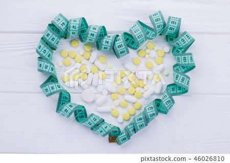 Heart-shaped measuring tape and pills. 46026810