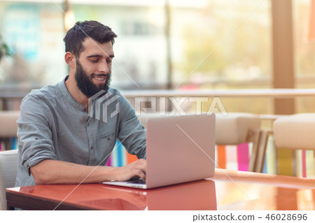 Half length portrait of successful bearded designer smiling at camera while working on freelance at Half length portrait of successful bearded designer smiling at camera while working on freelance at 46028696