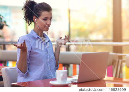 young attractive mixed race girl who is smiling looking at her laptop screen during video call young attractive mixed race girl who is smiling looking at her laptop screen during video call 46028699