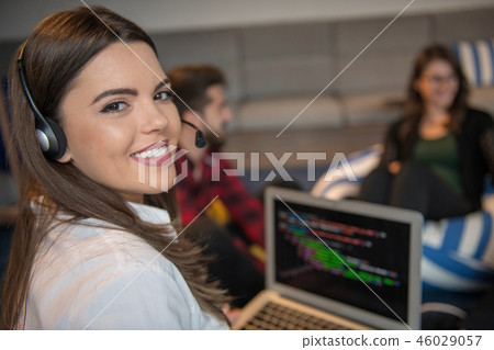 Portrait of businesswoman using laptop while colleague seen in background at creative office Portrait of businesswoman using laptop while colleague seen in background at creative office 46029057