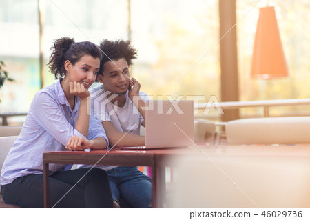 Interracial couple using tablet computer in coffee shop 46029736