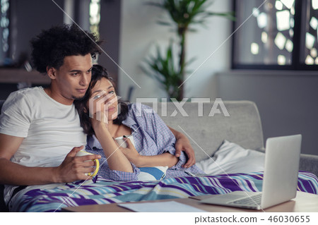 Young couple watching a movie on their laptop in bed 46030655