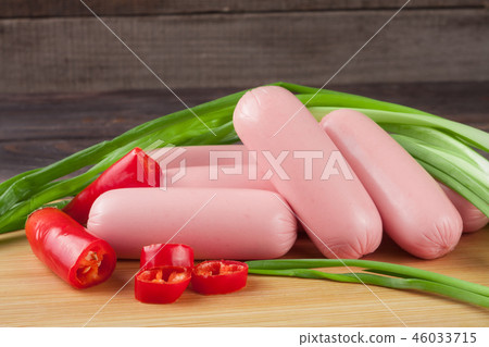 heap of sausages with spring onion and chilli on a cutting board wooden background heap of sausages with spring onion and chilli on a cutting board wooden background 46033715