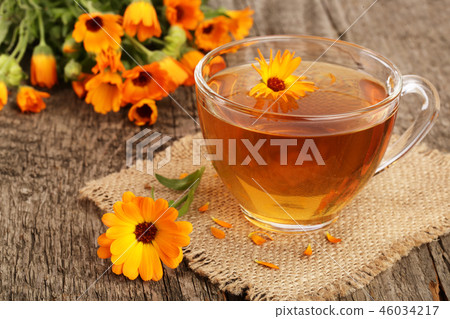 Calendula tea with fresh flowers on old wooden background Calendula tea with fresh flowers on old wooden background 46034217