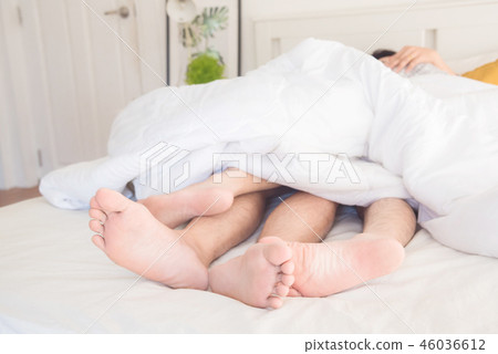 gay couple lying on bed under sheet at home  46036612
