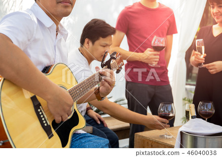 Group of friends having party with red wine and playing guitar outdoor. 46040038