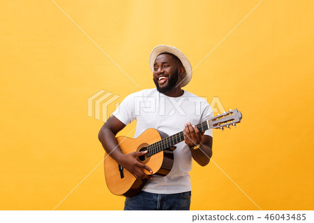 Handsome african american retro styled guitarist playing acoustic guitar isolated on yellow 46043485