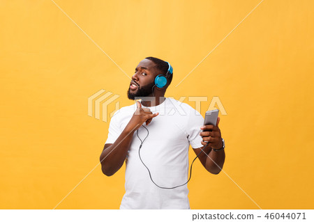 African American man with headphones listen and dance with music. Isolated on yellow background 46044071